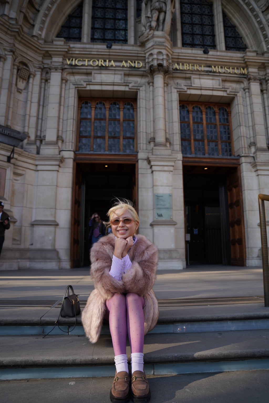 Front view of purple Dot Drift polka dot tights styled outside the V&A Museum