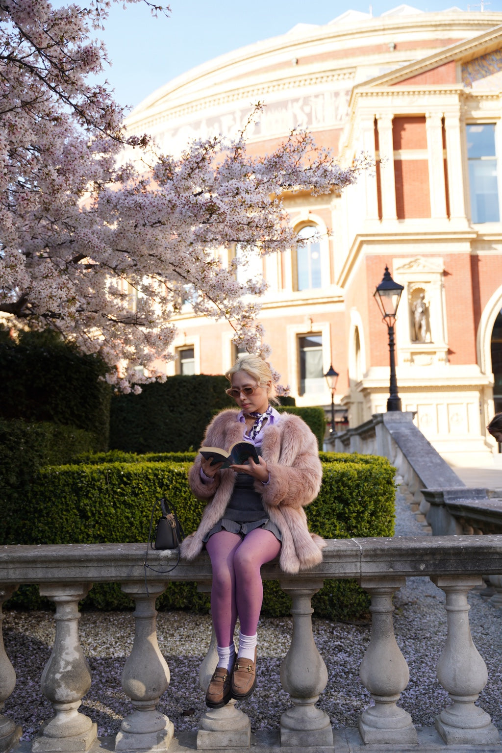 Woman styling purple Dot Drift polka dot tights beneath cherry blossom at the V&A Museum