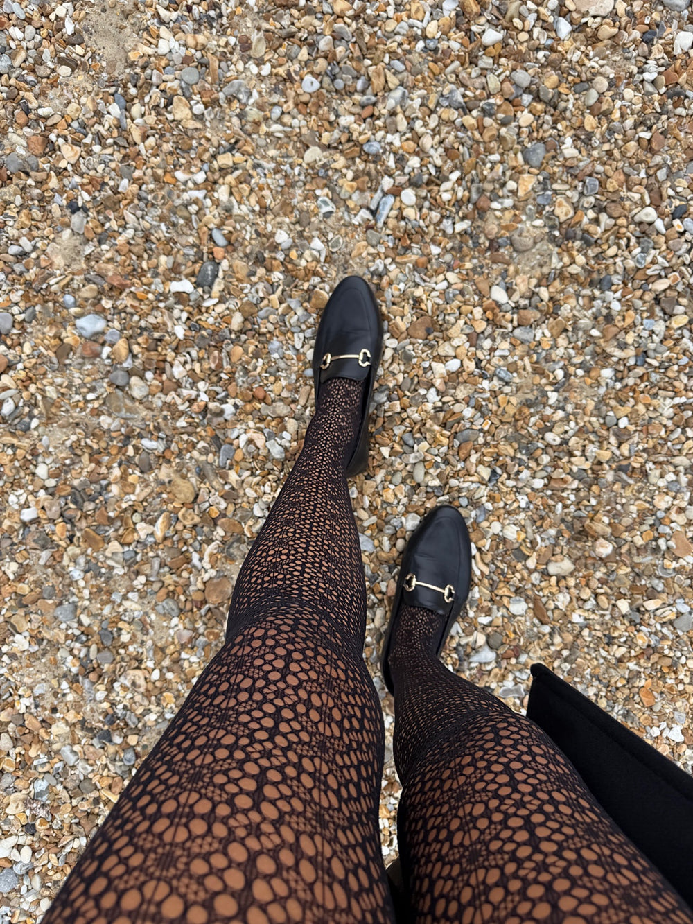Close-up of black Lace Loop openwork tights styled with black loafers