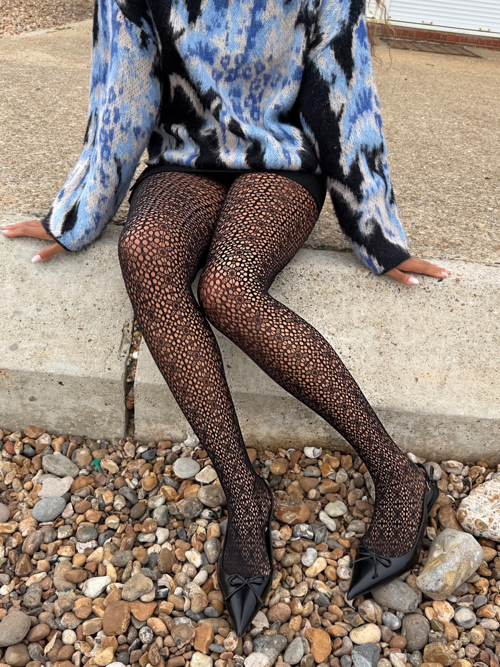 Model wearing black Lace Loop openwork tights with black pointed shoes