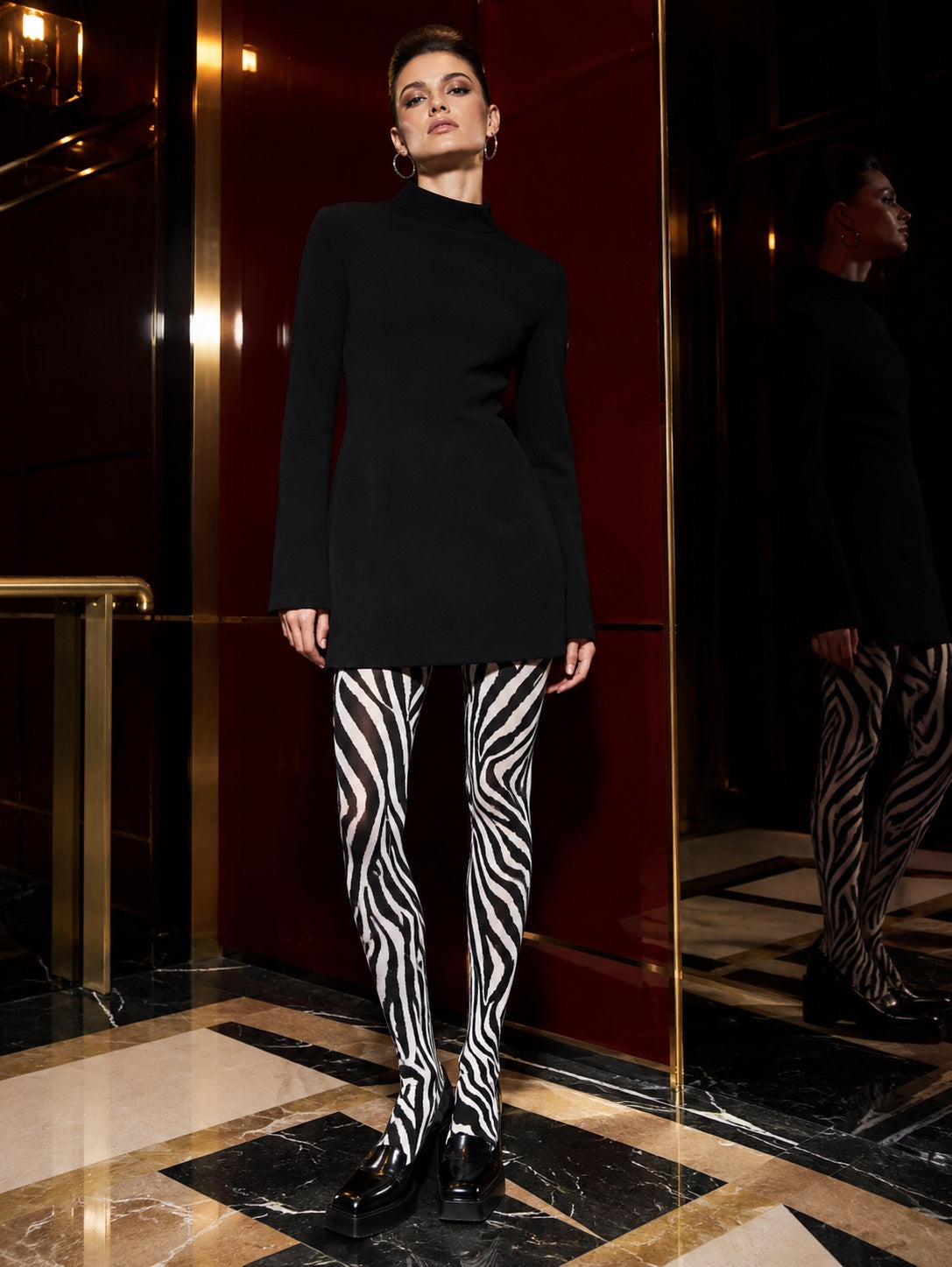 Black and white zebra print tights styled with a structured black mini dress and loafers